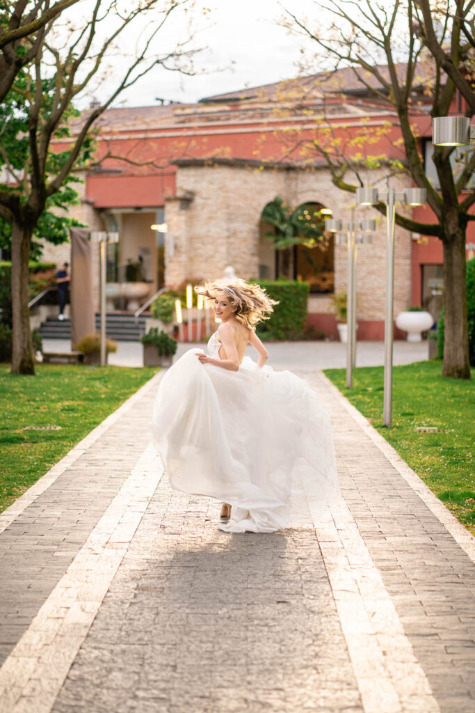 Lächelnde Braut im langen Kleid läuft vor einer großen Villa in Sirmione, Italien. Hochzeitsfotograf