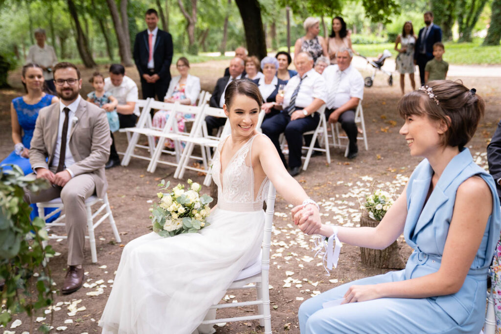 Die Braut und ihr Bruder halten sich bei der Trauung an den Händen. Sie schauen sich an und lächeln. Ein besonderes Porträt eines echten Getränks. Hochzeitsfotograf Wien