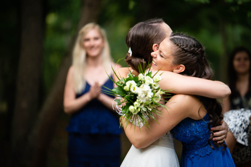 Die Braut wird von ihrer älteren Schwester umarmt, nachdem sie den Hochzeitsstrauß erhalten hat. Hochzeitsfotograf Wien