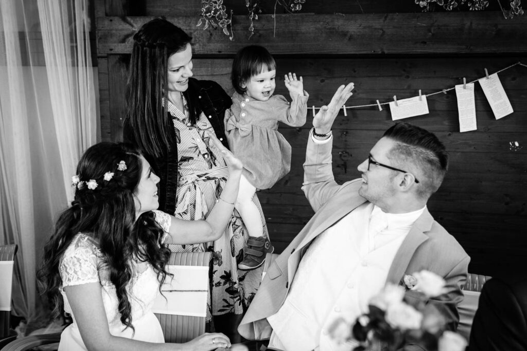 Ein seltener Moment. Das kleine Kind schenkt dem Bräutigam und den Bräuten beim Hochzeitsessen einen Kuchen. Hochzeitsfotograf Wien