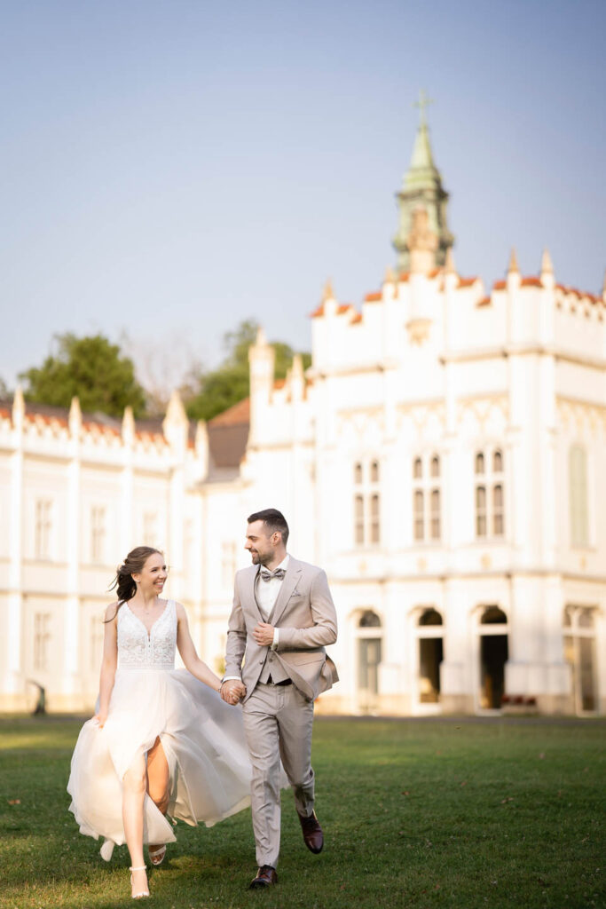 Lovely Wedding couple by a white castle. Running, smileing. Professional wedding photographer Vienna