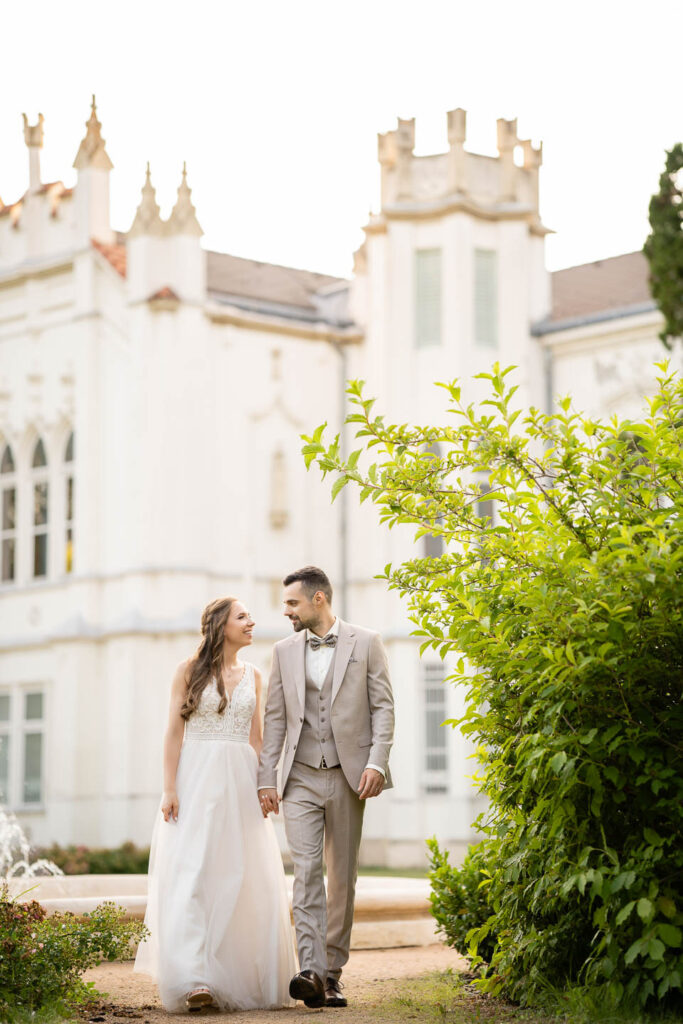 Lovely Wedding couple by a white castle. Walking, smileing. Professional wedding photographer Vienna
