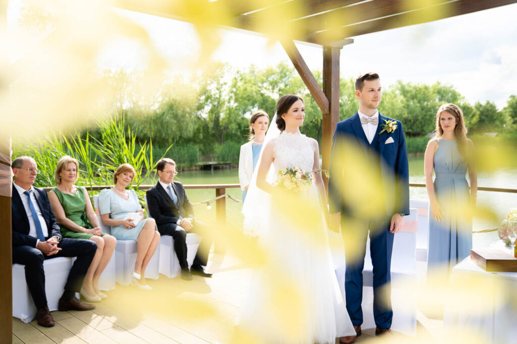 Ein wunderbarer Ort für die Trauung direkt am See mit Braut und Bräutigam. Künstlerisches Foto. Hochzeitsfotograf Wien