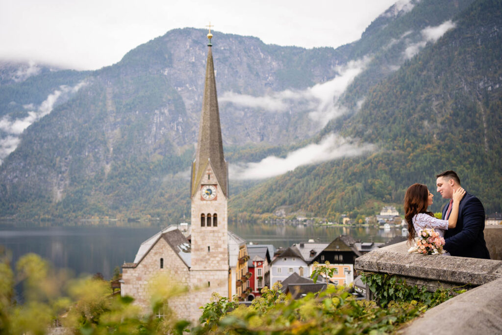Hochzeitspaar in Hallstatt mit einer Kirche im Hintergrund. Professioneller Hochzeitsfotograf Wien