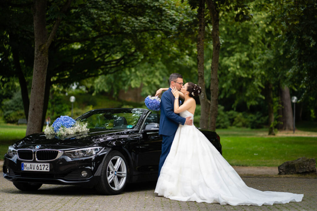 Elegantes Hochzeitspaar-Cabrio neben BMW in Düsseldorf. Professioneller Hochzeitsfotograf Wien