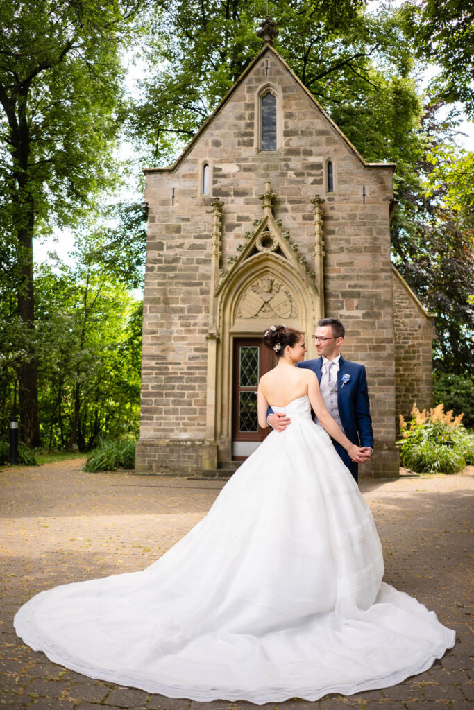 Elegantes Hochzeitspaar vor einer kleinen Kirche in Düsseldorf. Professioneller Hochzeitsfotograf Wien