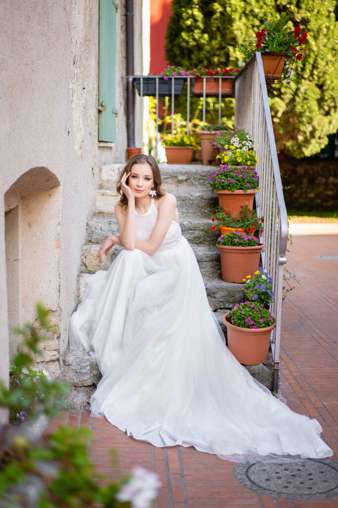 Eine schöne Braut sitzt neben den Blumen. Hochzeit in Italien, Sirmione, Wien. Professioneller Hochzeitsfotograf