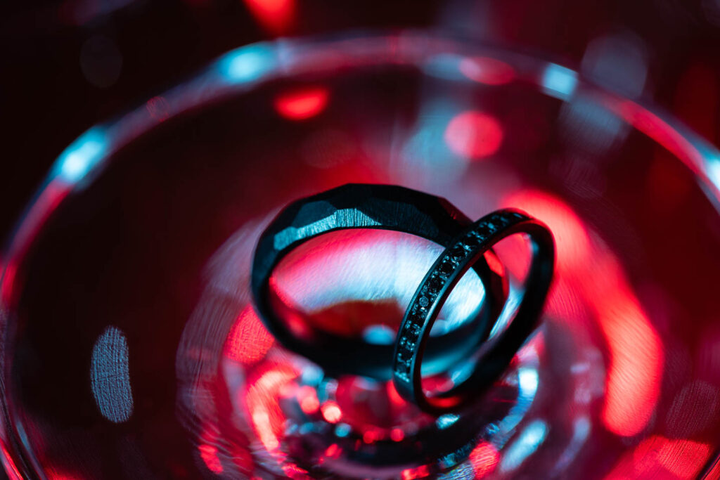 Seltene schwarze Eheringe mit besonderen schwarzen Diamanten auf buntem Hintergrund. Künstlerisches Foto. Hochzeitsfotograf Wien
