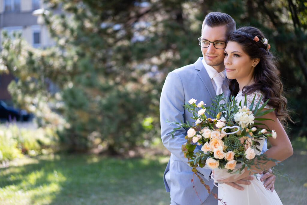 Das Brautpaar auf einem gemeinsamen Bild mit einem großen Blumenstrauß. Hochzeitsfotograf Wien