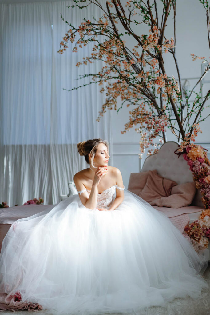 Schöne Braut sitzt in einem besonderen weißen Raum. Ein künstlerisches, sinnliches Porträt. Hochzeitsfotograf Wien