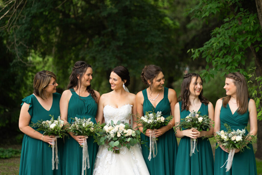 Auf einem Gruppenfoto schauen sich Braut und Brautjungfern in Uniform an. Hochzeitsfotograf Wien
