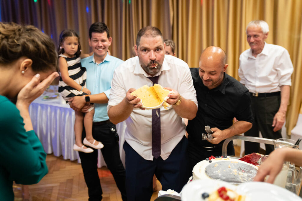 Der Ehemann beißt beim Hochzeitsessen in die Torte. Professioneller Hochzeitsfotograf Wien