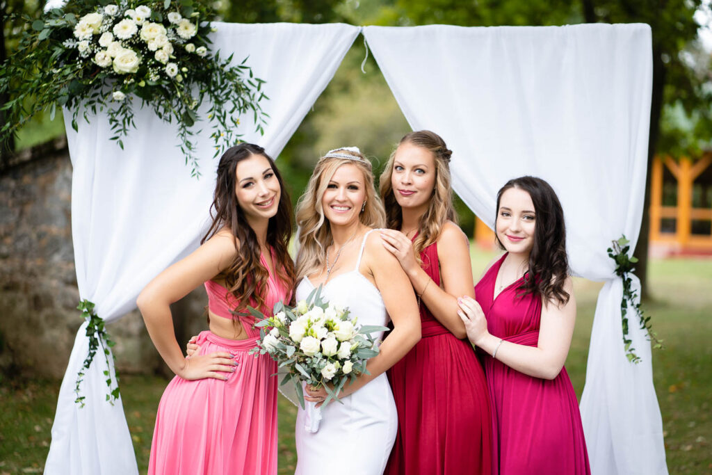 Schöne Braut und Brautjungfern vor dem Tor des Glücks. Professioneller Hochzeitsfotograf Wien