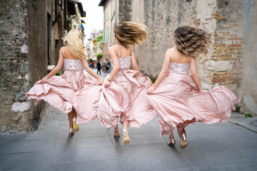 Womans are runing for the wedding in rose dress in Sirmione Italy. Professional Weddingphotograper